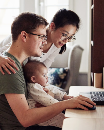 A young family of three sitting in front of a computer